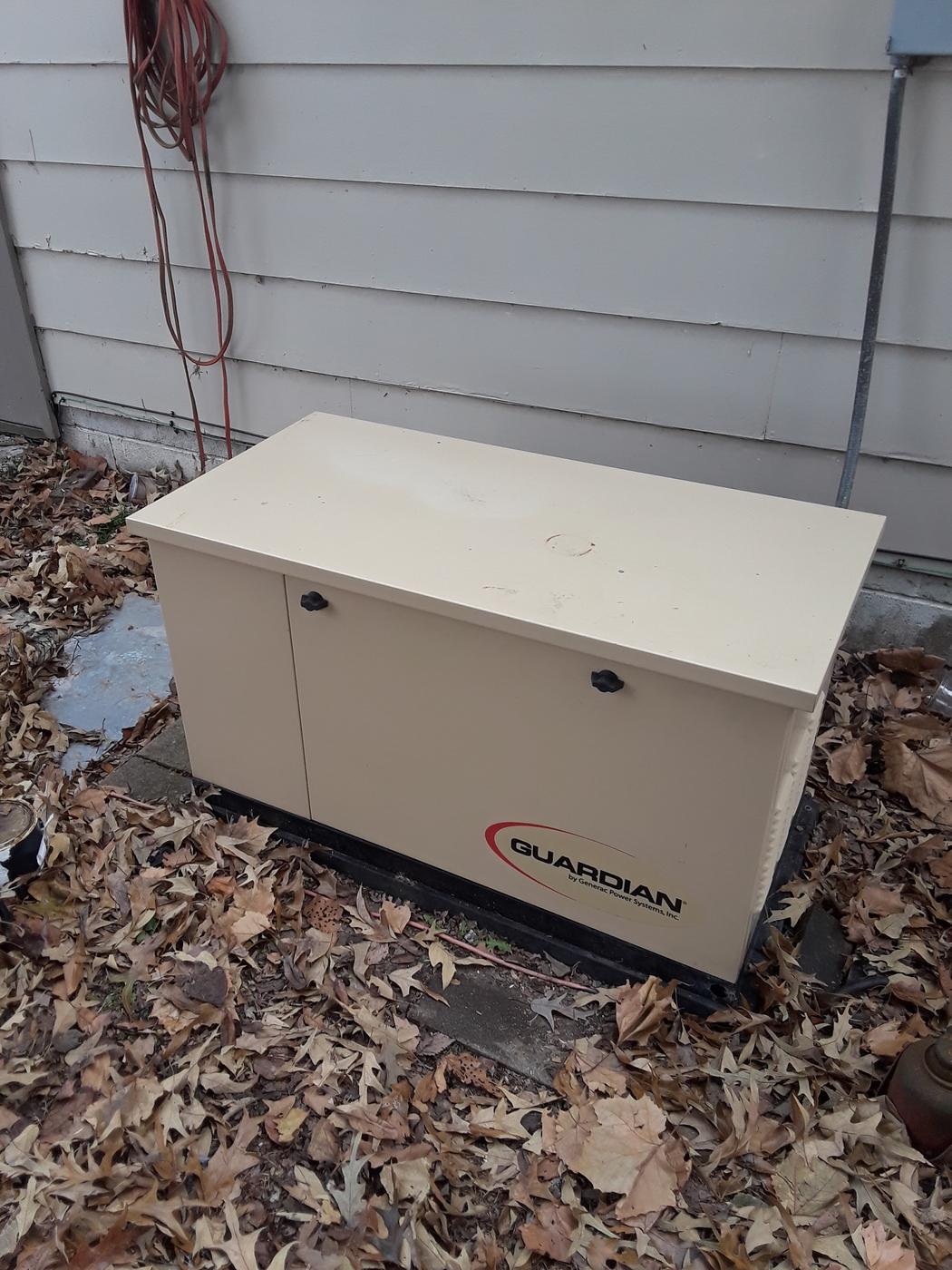 A standby generator installed against the side of a house