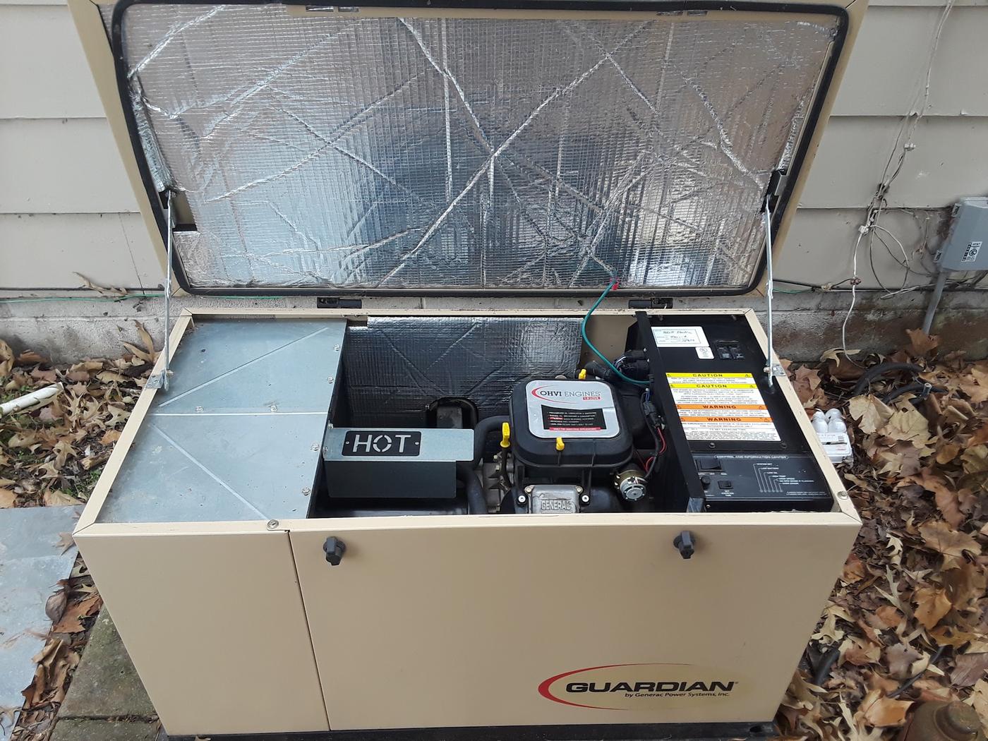 A standby generator with the lid open showing the engine and control panel